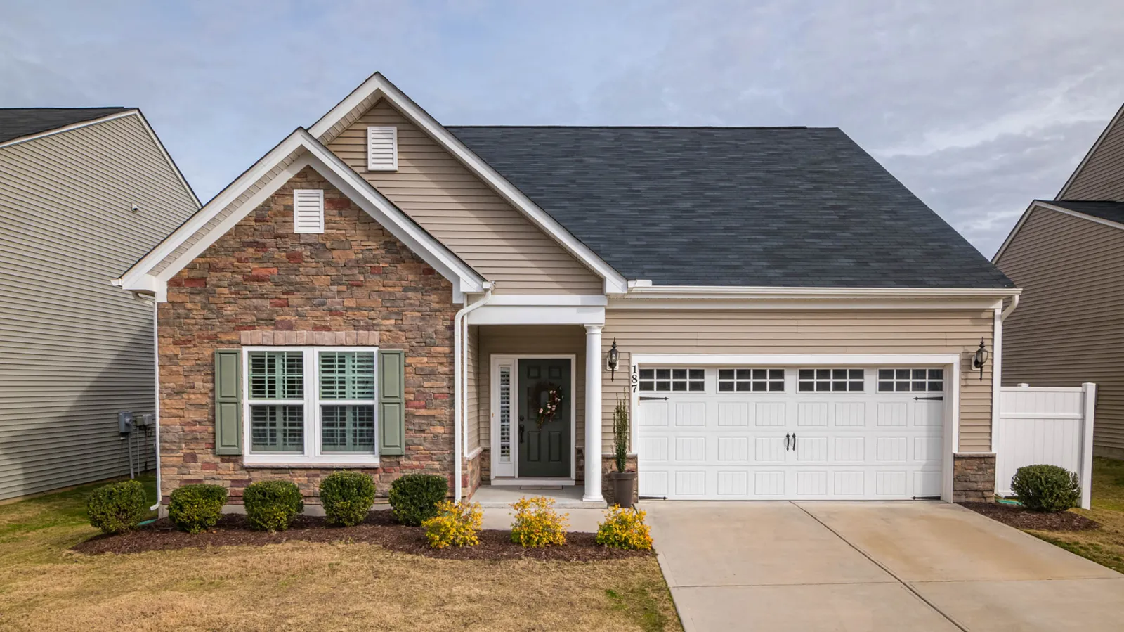 Ranch home of stone and siding beneath a dark gray asphalt shingle roof
